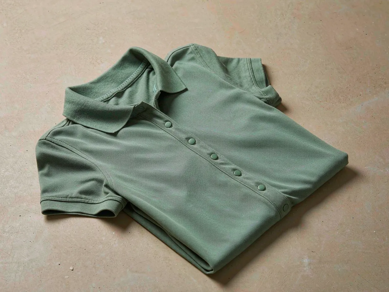 Gefaltetes salbeigrünes Piqué-Poloshirt mit Flachstrickkragen, Knopfleiste mit schlichten Knöpfen und gerippten Manschetten.
